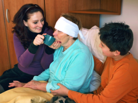 Woman and a boy assisting a senior in drinking